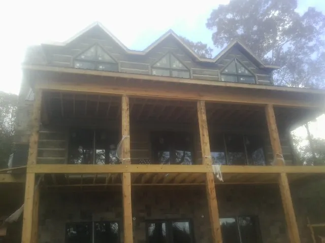 Dormers and porch framing on a large log home under construction — Roof Coating work by our crew in Seaford