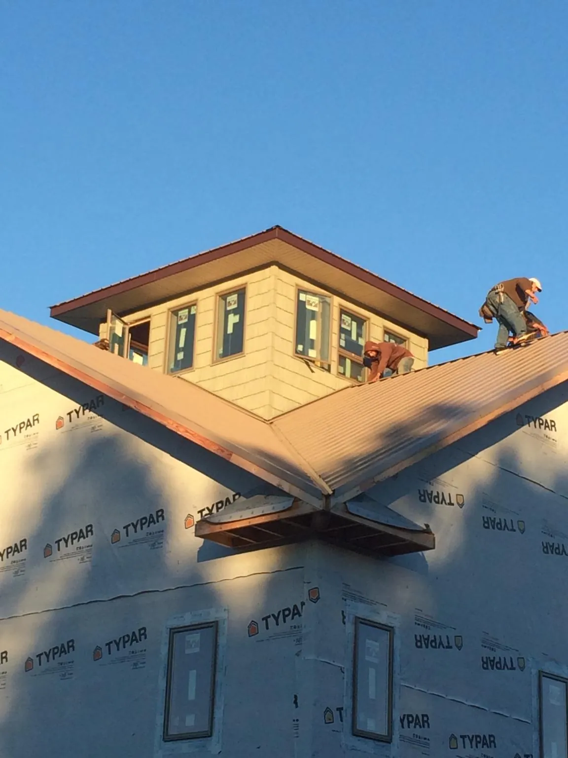Roofers working around a rooftop cupola on a new metal roof at sunset — Roof Waterproofing in Seaford by Roofing Brothers